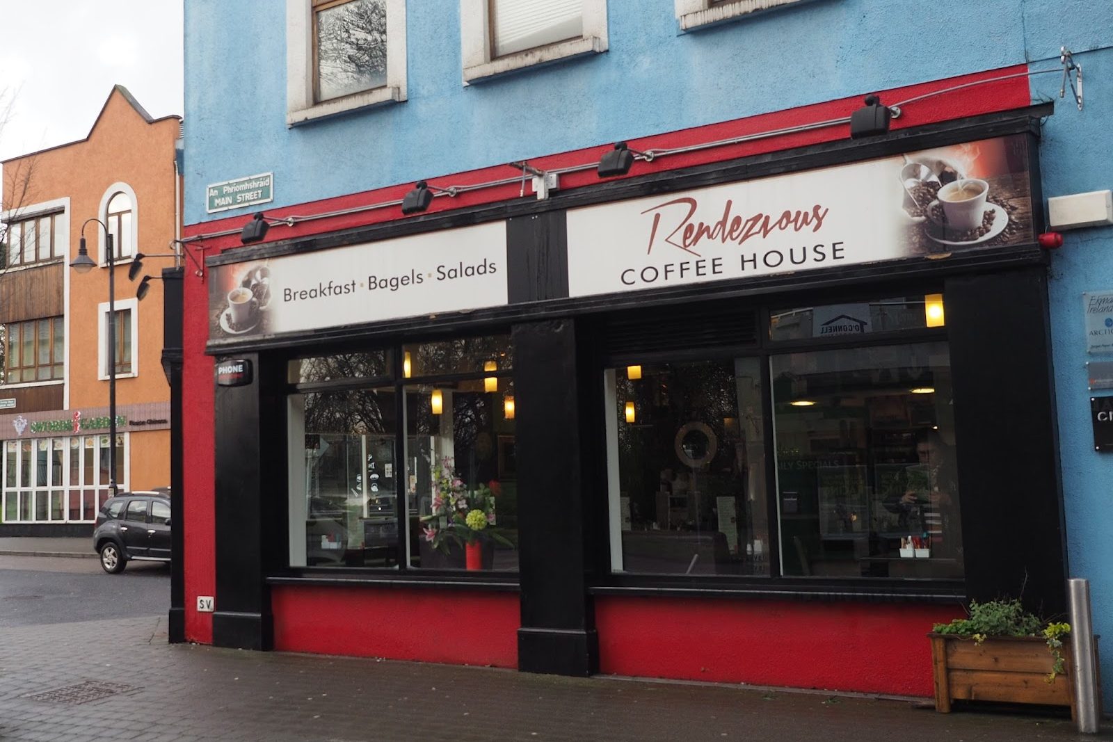 The red-trimmed Rendezvous Coffee House shopfront on Main Street, Ongar, with its Breakfast · Bagels · Salads sign and flowers in the window